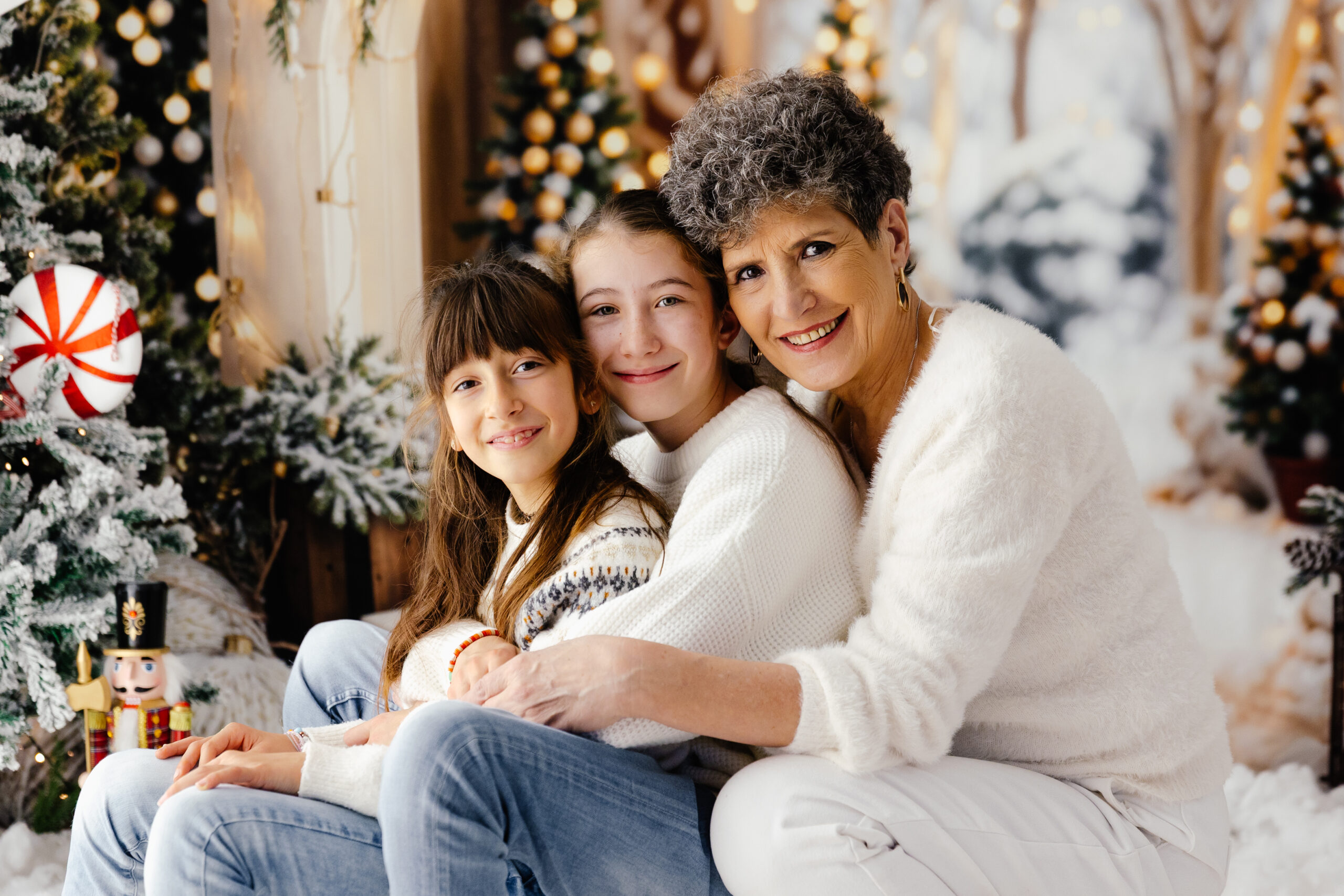 Portrait de famille sous l’arche de sapins enneigés du décor de Noël